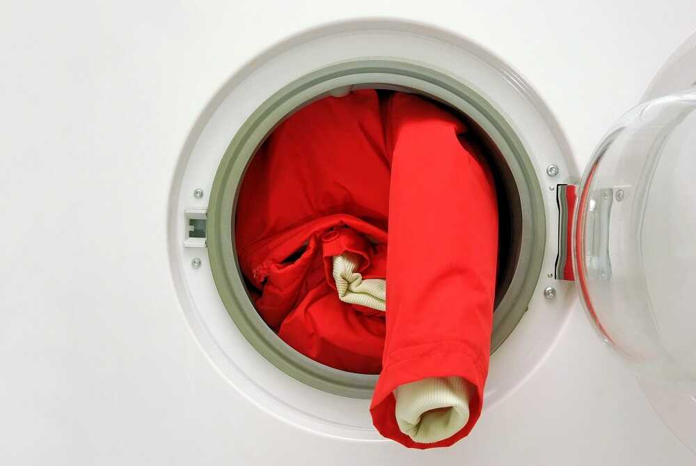 Красная куртка торчит из стиральной машины