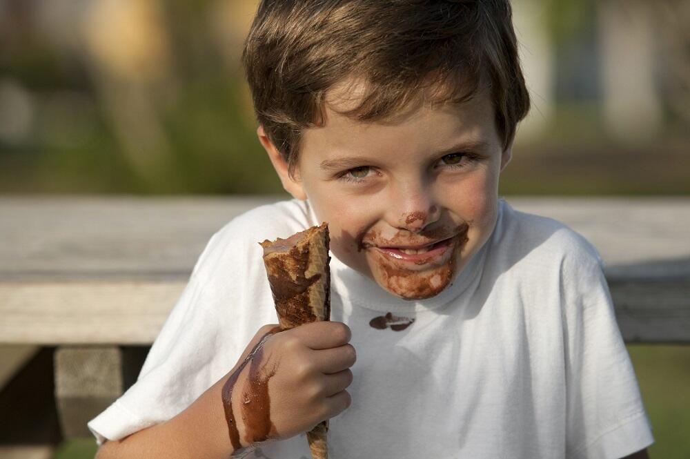 Мальчик ест шоколадное мороженое