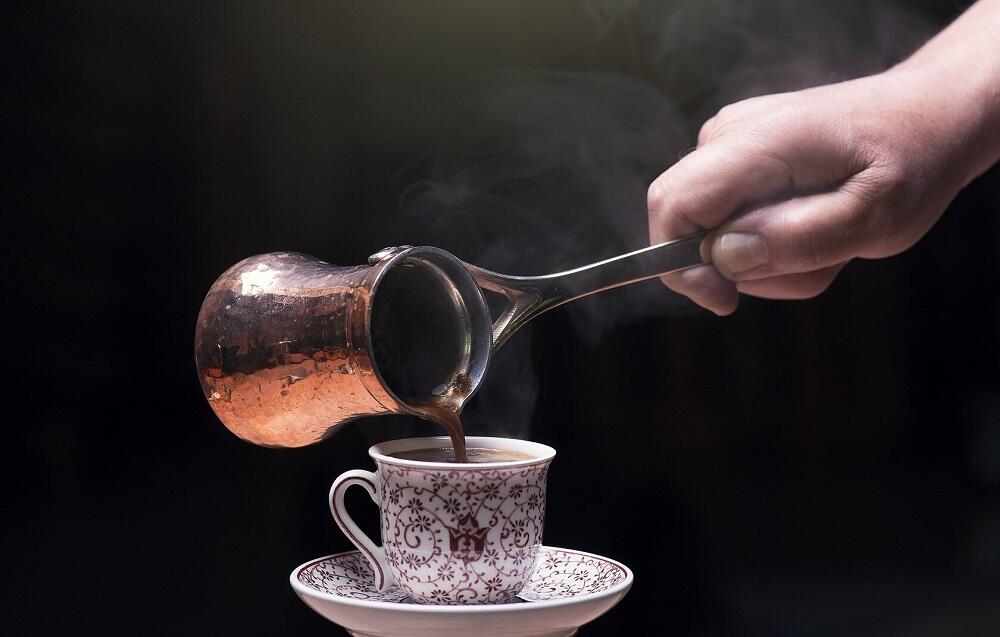 Человек наливает кофе из турки
