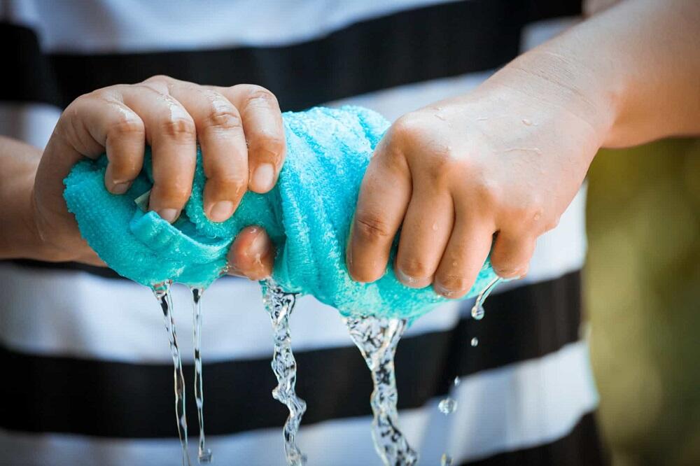 Человек отжимает мокрое полотенце